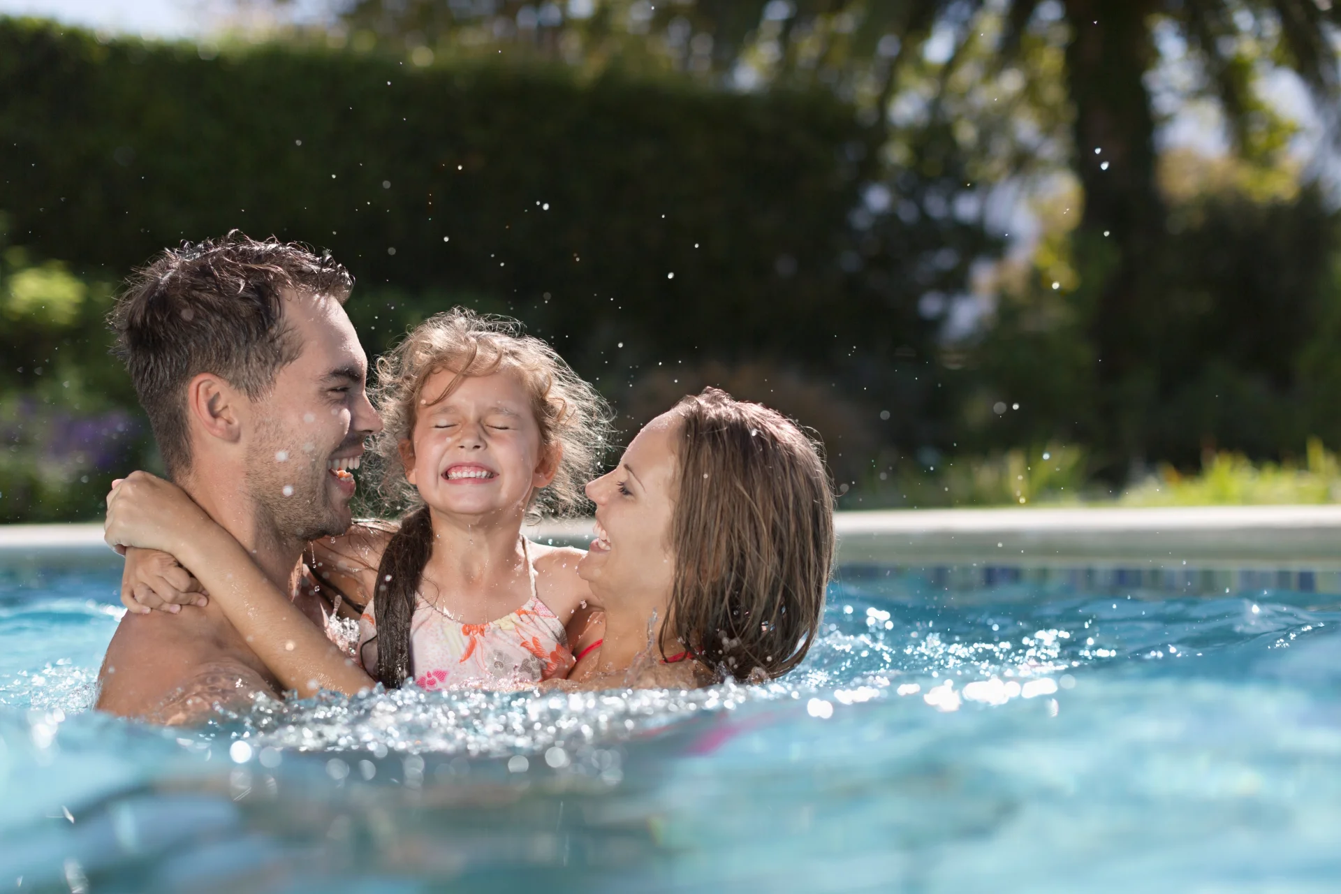 mother father and young daughter in a pool